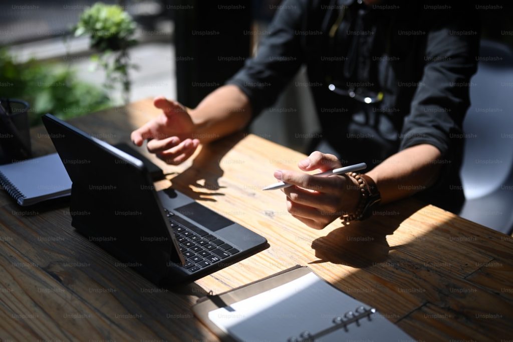 Professional explaining a strategy at a wooden desk with a tablet and notebook, BURG+CO. Marketing