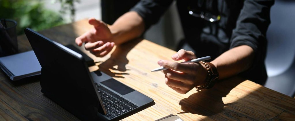 Professional at a wooden desk with a tablet, pen and notebook, BURG+CO. Marketing contact us