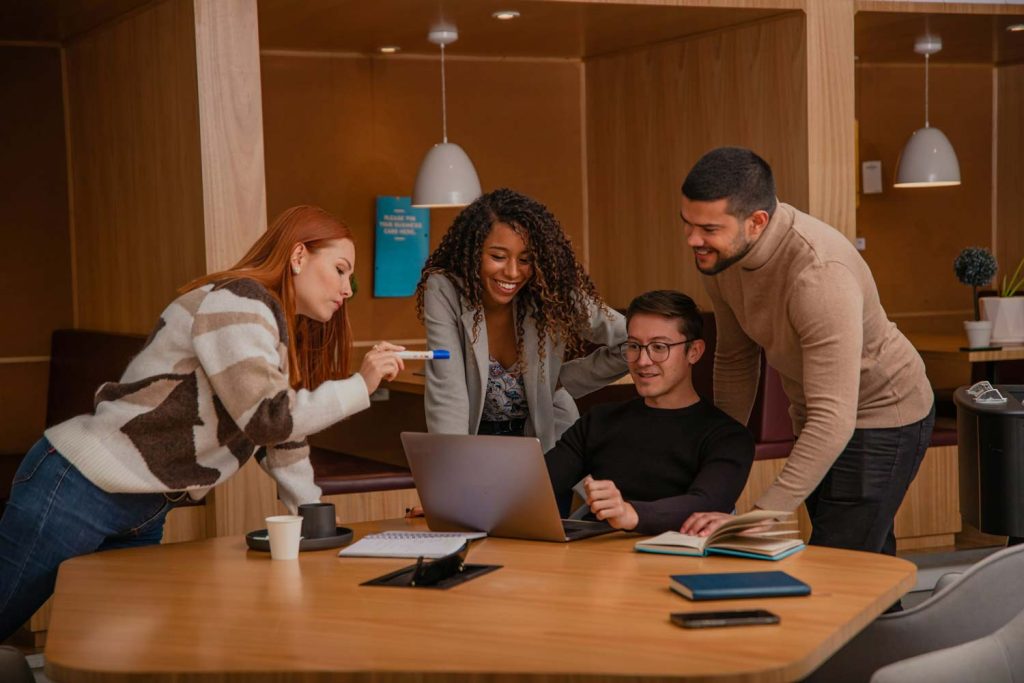 Smiling team collaborating around a laptop in a modern office, BURG+CO. Marketing team