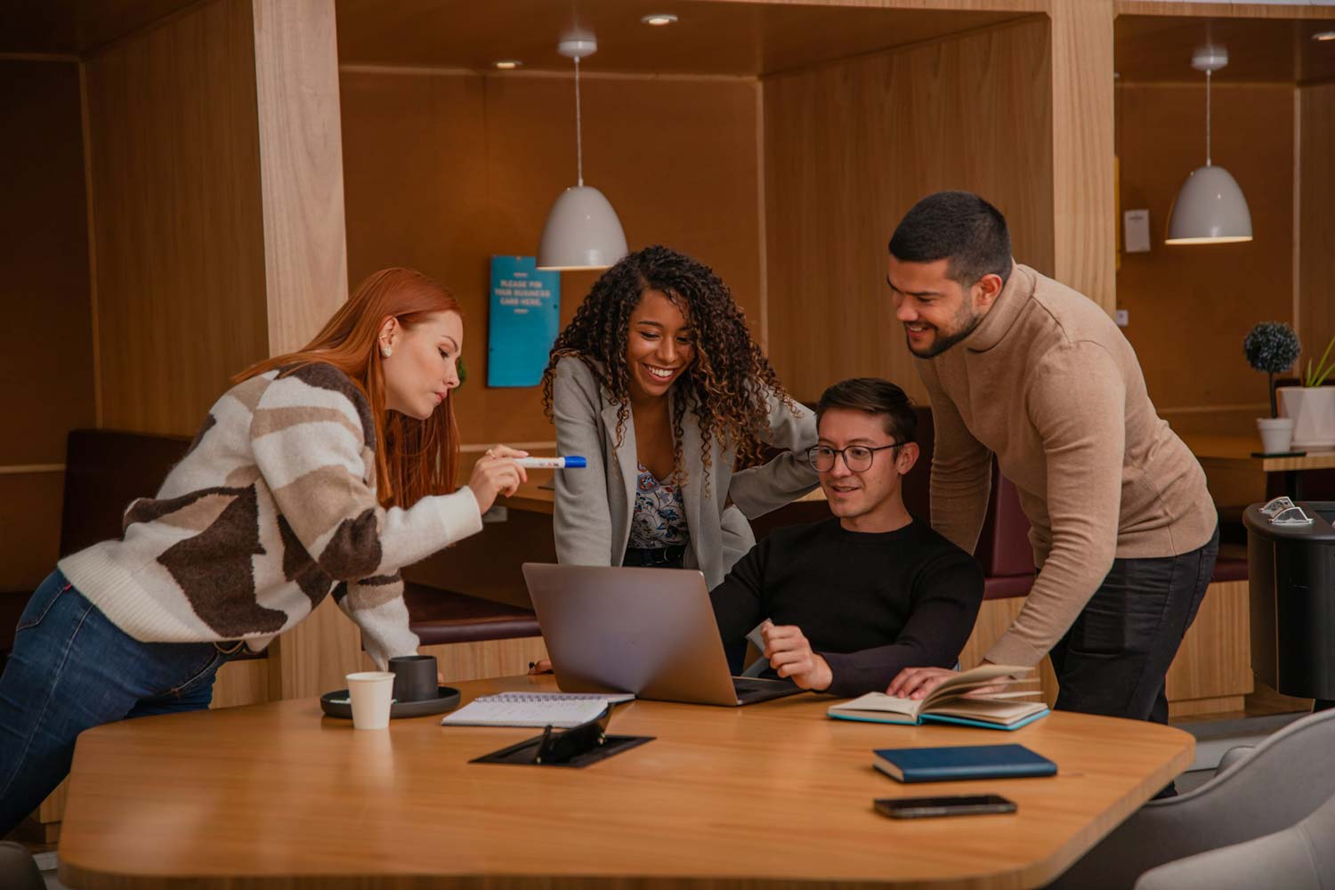 Smiling team collaborating around a laptop in a modern office, BURG+CO. Marketing team